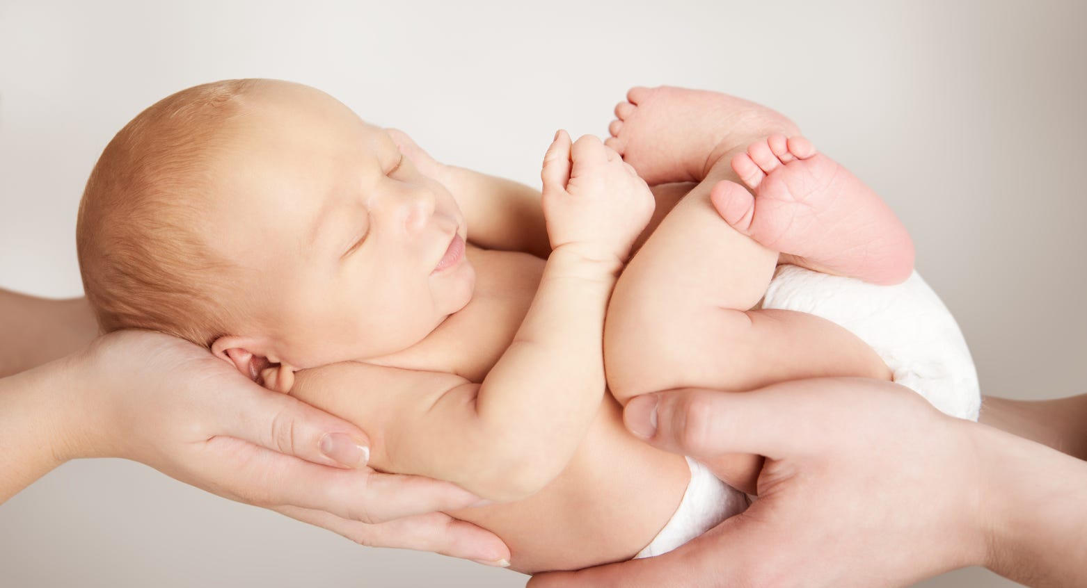 Säugling wird liebevoll in den Händen gehalten - Wohlfühlen - Geborgenheit © Adobe Stock: inarik